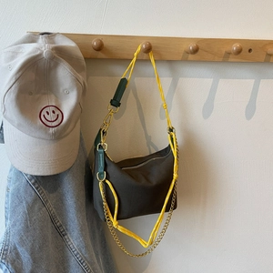 Detail of olive green nylon bag featuring yellow woven strap and vintage metal chain link