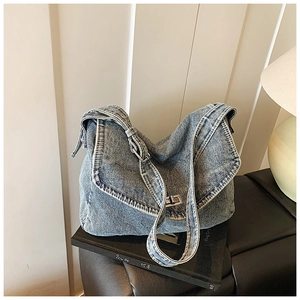 Dettaglio della borsa in denim blu con trama lavata vintage e chiusura a scatto in metallo