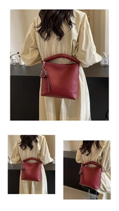 Detail of red woven bucket bag showing intricate texture, chain strap, and heart pendant