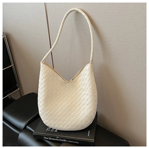 Détail du sac hobo blanc tissé avec texture en losange sur un support noir élégant