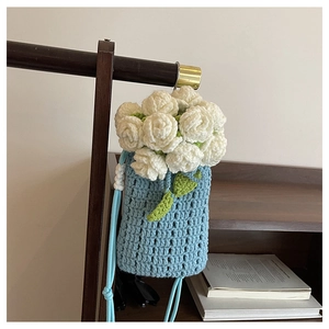 Detail of hand-crocheted light blue bucket bag with white rose floral decorations