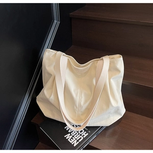 Detail of a large off-white canvas tote bag with JUMAITU logo on wooden steps