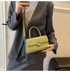 Detail of trendy grass green patent leather crossbody bag with silver buckle worn on a blazer