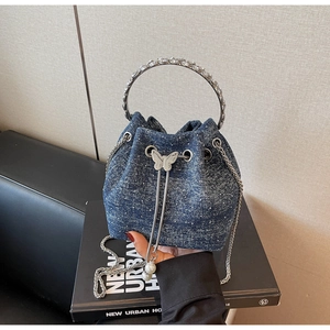 Detail of blue denim bucket bag with rhinestone metal handle and butterfly drawstring buckle
