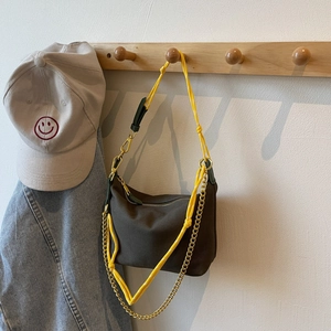Detailed close-up of dark brown nylon dumpling bag with yellow rope and gold chain strap