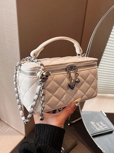 White quilted box bag with silver heart charm and chain strap shown in lifestyle setting