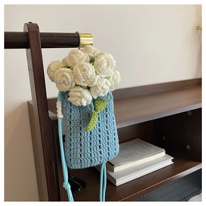 Close-up of handmade blue knit phone bag featuring detailed white crochet flower petals