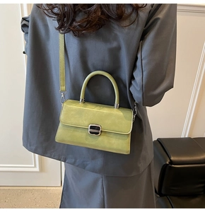 Side view of structured light green handbag styled with a grey blazer for daily outfit