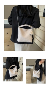 Detail view of woven texture cream bucket bag with heart rivet charm and silver chain strap