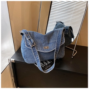 Dettaglio della borsa a tracolla in denim blu con chiusura a scatto in metallo e tracolla