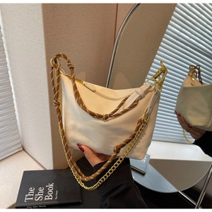 Detail of a beige nylon hobo bag with a decorative woven strap and gold chain detail