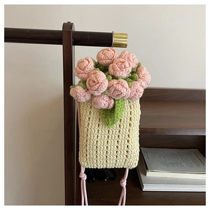 Detail of handmade crochet phone bag with pink knit roses and cream yellow weave