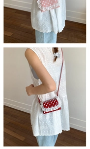 Detailed view of the double-layered white lace trim and polka dot pattern on the crossbody bag
