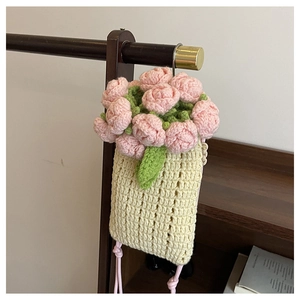 Detailed view of handmade cream crochet bag with pink floral accents and knit texture