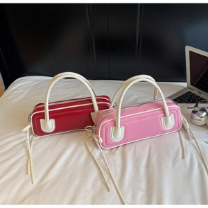 Two small bowling handbags in pink and red colors on a bed with lifestyle accessories