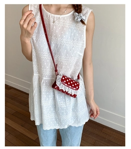 Girl wearing a red polka dot crossbody bag with white lace trim and slim shoulder strap