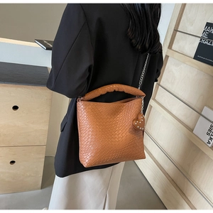 Model wearing brown crocodile pattern bucket bag with silver chain and heart charm