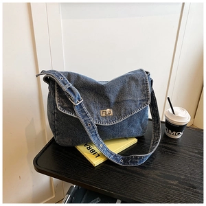 Dettaglio borsa in denim blu con chiusura a rotazione argento e tracolla regolabile