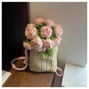 Close-up of handmade crochet bucket bag with pink floral roses and beige woven texture