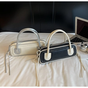 Detail of minimalist leather baguette bags with contrast handles and long tassel zippers