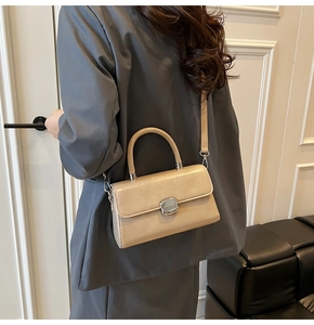 Chic cream leather crossbody bag with silver buckle worn by model in urban interior