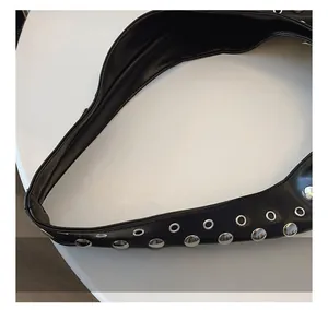 Detailed close-up of glossy black leather handle with silver rivets and metal eyelets