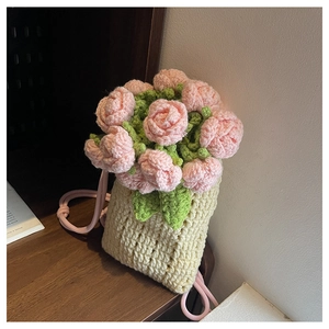 Detailed close-up of handmade crochet bucket bag with 3D pink rose and green leaf accents