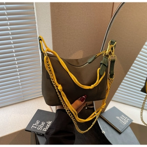 Close-up of brown nylon dumpling bag with yellow rope strap and golden chain detail