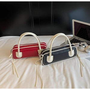 Detail view of stylish baguette bags in red and black with white contrast leather trim