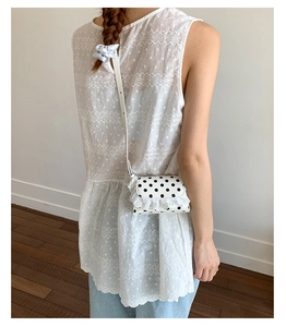 Close-up of polka dot mini crossbody bag with ruffled lace trim worn by a child