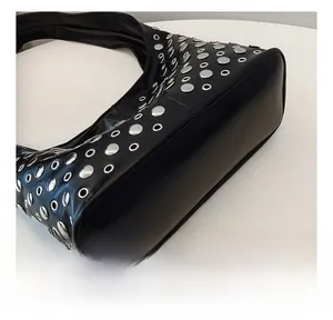 Close-up of black leather punk bucket bag featuring silver metal rivets and eyelet details