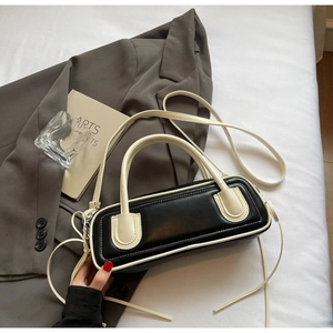 Close-up of contrast black and white leather baguette bag on a neutral blazer background