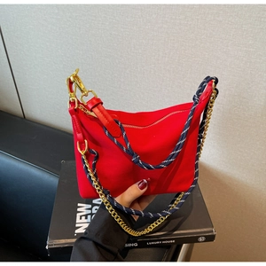 Detail of red nylon crescent bag featuring gold chain and blue woven rope strap