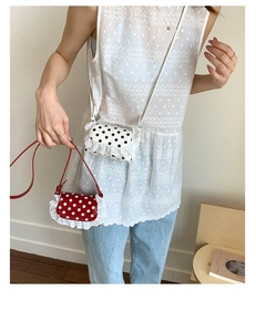 Close-up of mini polka dot lace crossbody bags in red and white on a model