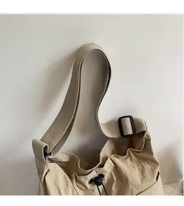 Detail view of khaki shoulder bag featuring adjustable black buckle and drawstring closure