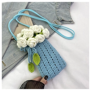 Detail of handmade crochet phone bag with white 3D floral roses and blue knitted texture