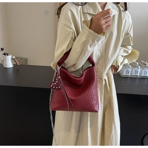 Detail of burgundy woven bucket bag with silver chain strap and heart charm decoration