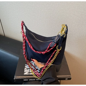 Detail of navy nylon hobo bag featuring red white rope handle and gold chain strap