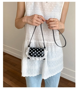 Close-up of sweet polka dot mini crossbody bag with delicate white lace trim detail