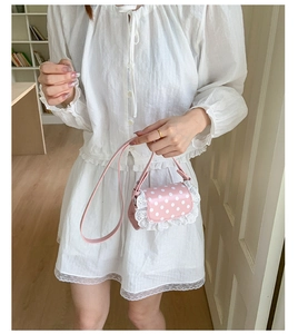 Pink polka dot mini bag with white lace trim held by hand showing compact dimensions