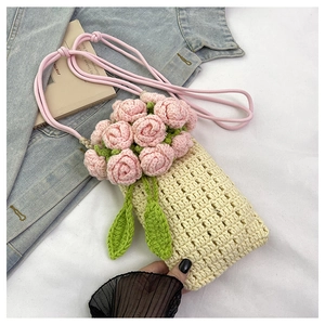 Close-up of handmade knit phone bag with 3D pink rose decor on blue denim background