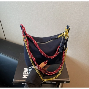 Detail of navy nylon crescent bag with woven climbing rope and gold chain strap