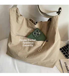 Close-up of front zipper pocket on khaki nylon tote bag showing phone storage capacity