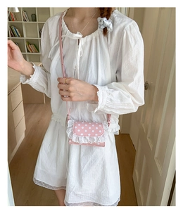 Detailed view of pink polka dot crossbody bag with lace trim and slim shoulder strap