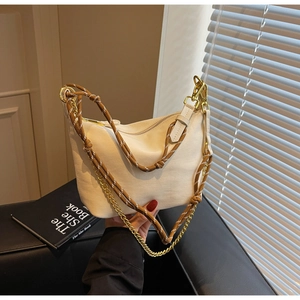 Detail view of off-white nylon dumpling bag with woven strap and gold chain accessories