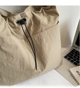 Detailed close-up of khaki pleated bucket bag showing metallic eyelets and drawstring cord