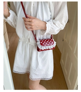 Close-up of red polka dot mini bag with white lace trim and slim crossbody strap detail