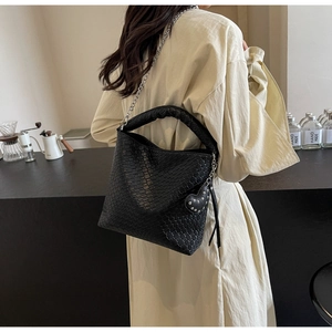 Detail of black woven bucket bag with silver chain strap and studded heart charm