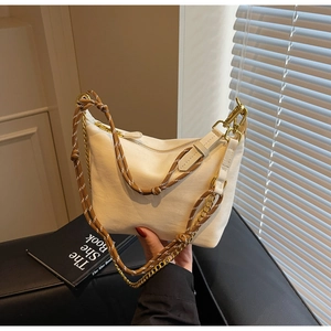 Detail of a creamy white nylon bag with dual-texture woven rope and gold chain strap on sofa