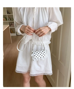 Detailed view of small white polka dot bag with lace trim worn by a child